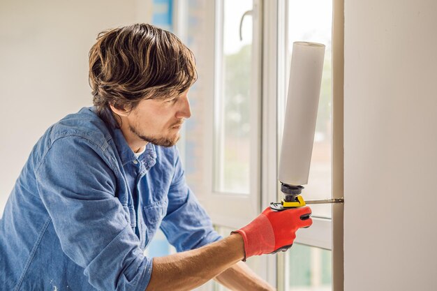 Mann in einem blauen Hemd macht Fensterinstallation.