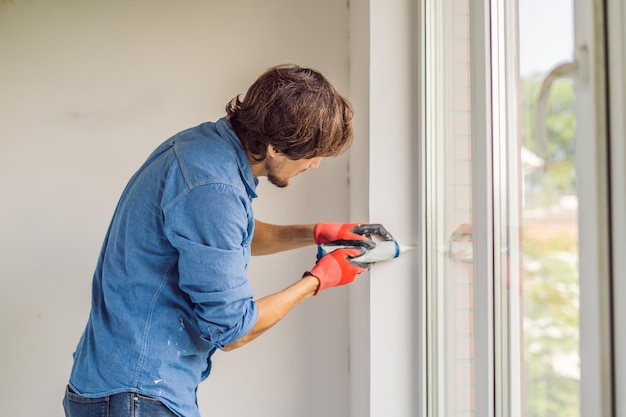 Mann in einem blauen Hemd macht Fensterinstallation.