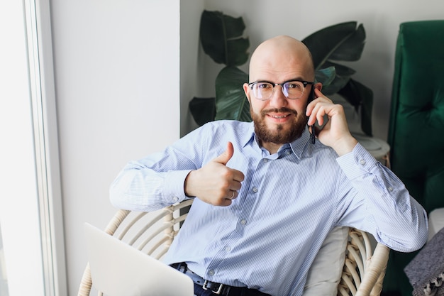 Mann in einem blauen Hemd mit einem Bart, der an einem Laptop zu Hause arbeitet Bleiben Sie zu Hause