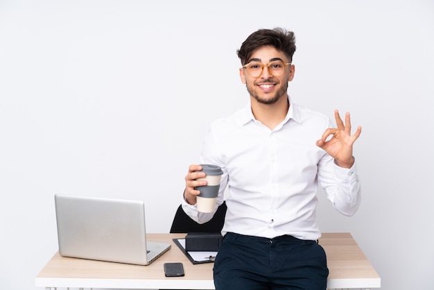 Mann in einem Büro lokalisiert auf weißer Wand, die ein ok Zeichen mit den Fingern zeigt