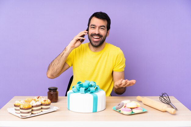 Mann in einem Tisch mit einem großen Kuchen, der ein Gespräch mit dem Handy mit jemandem führt