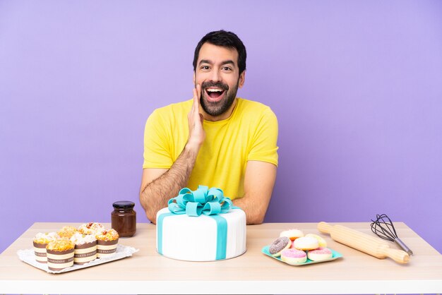 Mann in einem Tisch mit einem großen Kuchen mit Überraschung und schockiertem Gesichtsausdruck