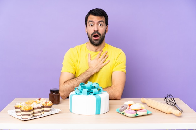 Mann in einem Tisch mit einem großen Kuchen überrascht und schockiert, während er richtig schaut