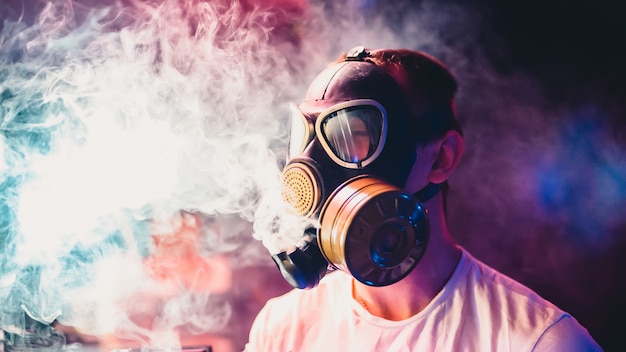 Mann in einer Gasmaske raucht eine Wasserpfeife und atmet eine Rauchwolke