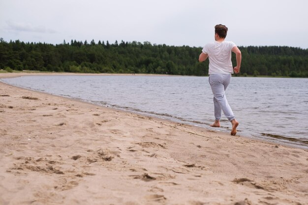 Mann in Fitnesskleidung läuft am Sandstrand entlang