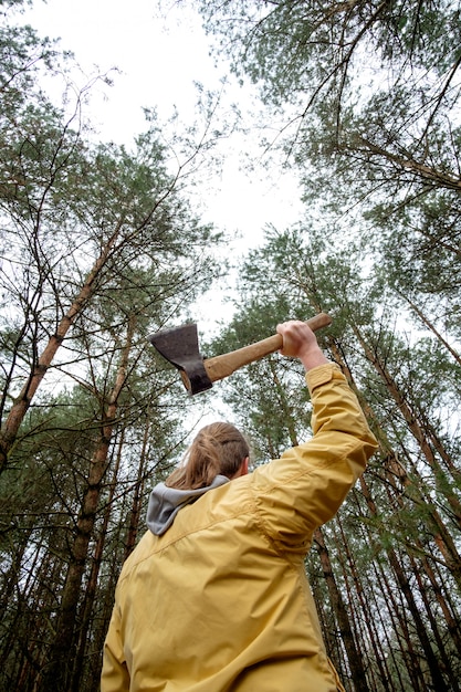 Mann in gelber Jacke im Wald mit Axt