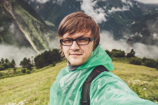 Mann in Gläsern, die selfie mit grünen Grasbergen nehmen