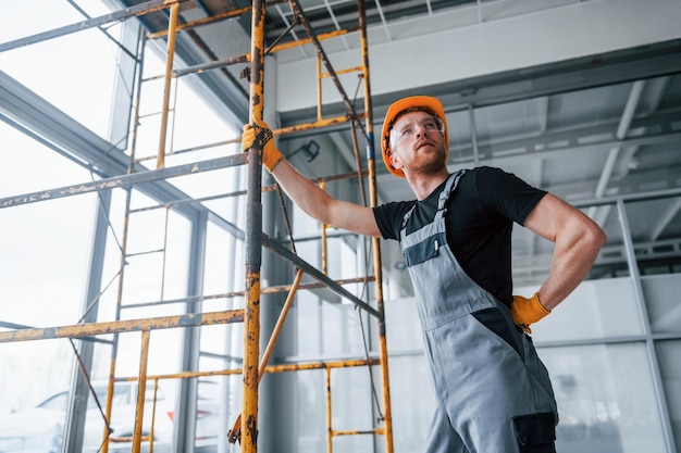 Mann in grauer Uniform arbeitet tagsüber mit Bauarbeiten im Innenbereich in modernen großen Büros