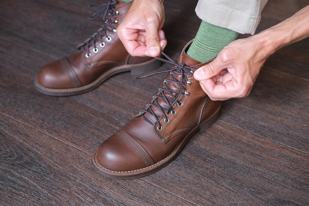 mann in grünen socken hat schnürsenkel an seinen neuen stylischen vintage braunen arbeitsstiefeln gebunden