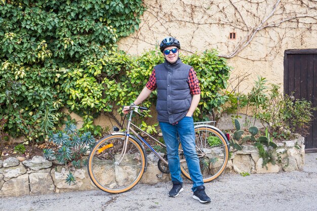 Mann in Helm und Brille bleibt auf dem Fahrrad im Garten