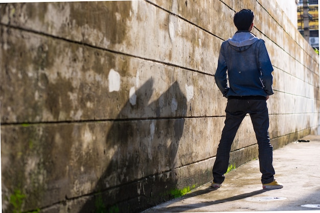 Mann in Jeans Kleidung steht auf dem Boden vor der zerstörten Mauer.