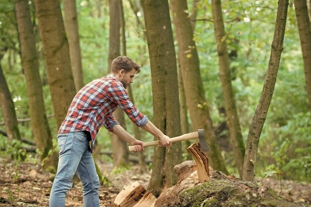 Mann in Jeans und kariertem Hemd, der mit Axtkraft Holz hackt