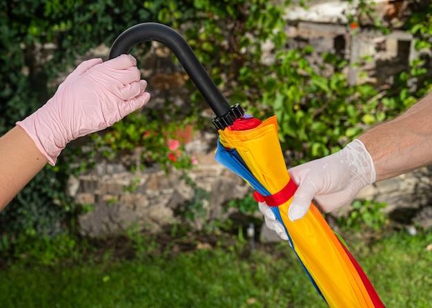 Mann in Schutzhandschuhen teilt einen Regenschirm mit einer anderen Frau in Handschuhen