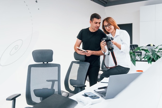 Mann in schwarzer Kleidung, der Fotos auf der Kamera des Fotografen der Frau anschaut