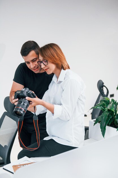 Mann in schwarzer Kleidung, der Fotos auf der Kamera des Fotografen der Frau anschaut