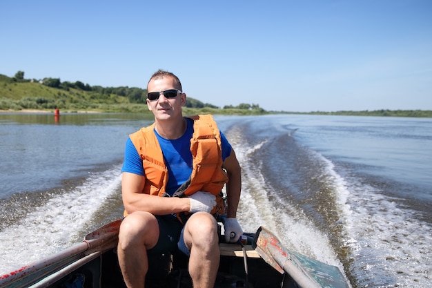 Mann in Schwimmweste auf dem Boot bewegt sich schnell