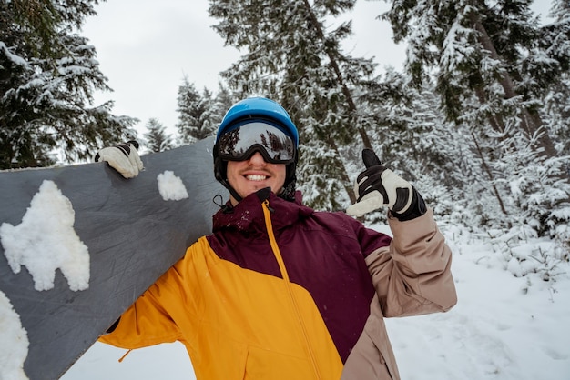 Foto mann in skiausrüstung, schutzbrille tragend. abenteuer zum wintersport. snowboardermann, der am berg wandert. auf der suche nach powder zum freeriden.