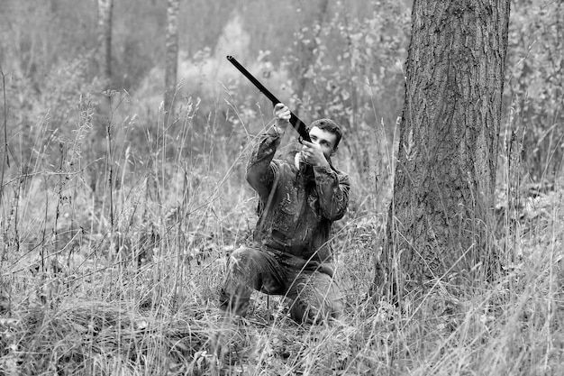 Mann in Tarnung und mit Jagdgewehr im Wald auf Frühjahrsjagd