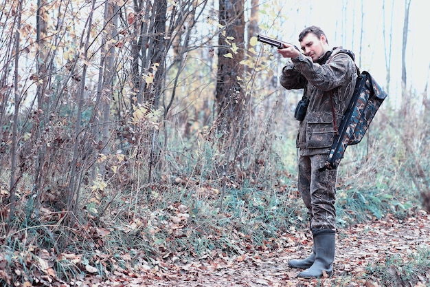 Mann in Tarnung und mit Jagdgewehr im Wald auf Frühjahrsjagd