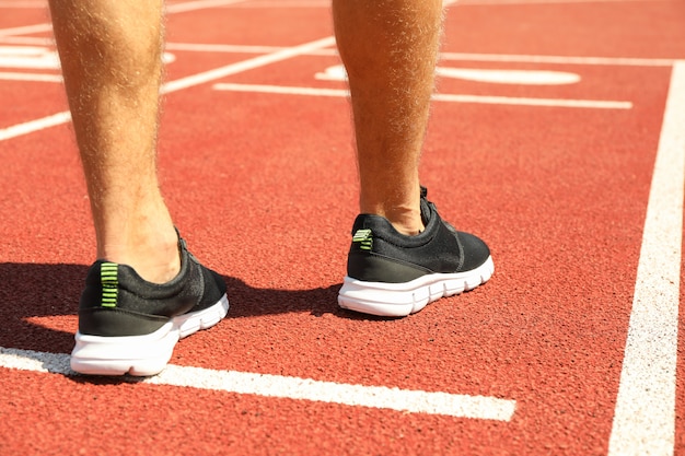 Mann in Turnschuhen auf roter athletischer Laufbahn, Nahaufnahme