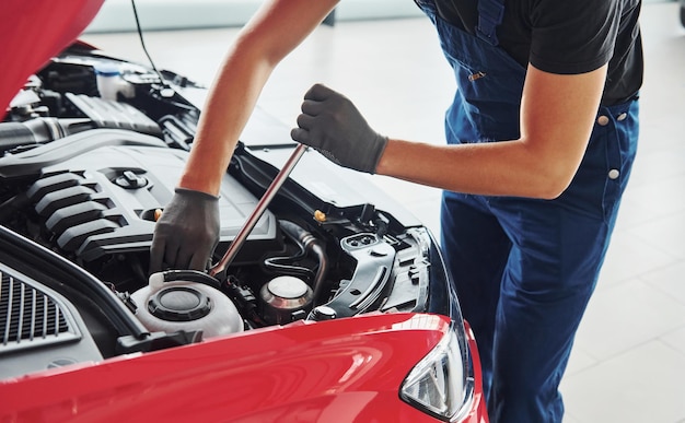 Mann in Uniform arbeitet mit kaputtem Auto Konzeption des Autoservices