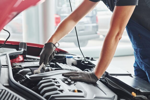 Mann in Uniform arbeitet mit kaputtem Auto Konzeption des Autoservices