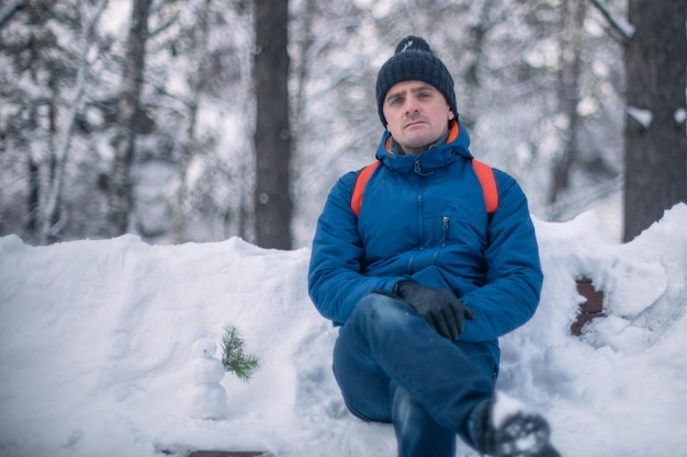 Mann in Winterjacke, der im verschneiten Winterwald spazieren geht, verschneiter Wintertag