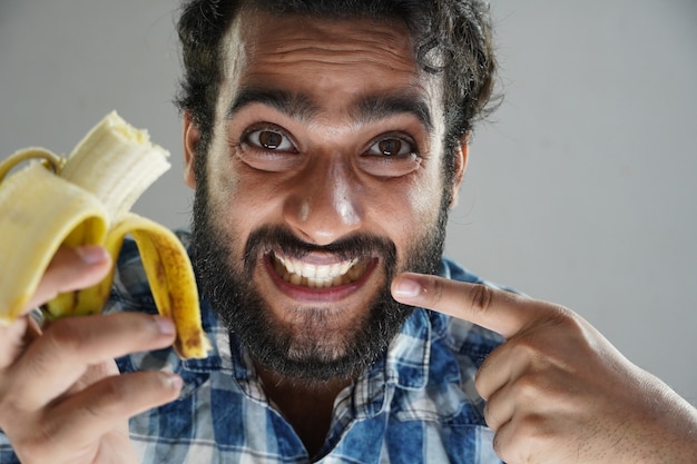 Mann isst Banane und zeigt Zähne