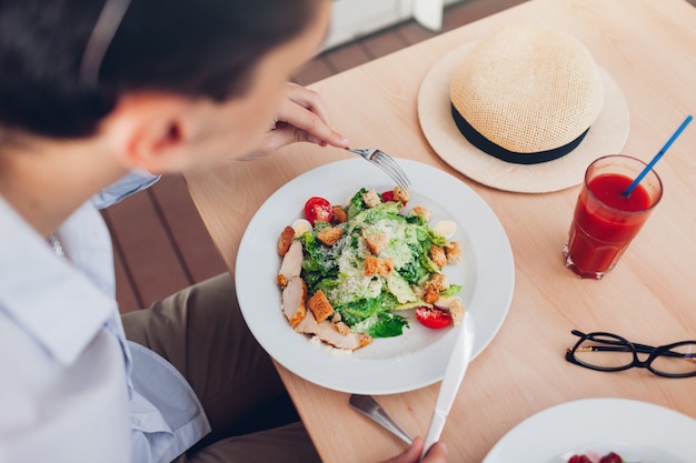 Mann isst Caesar Salat und trinkt Tomatensaft im Restaurant. Reisender, der im Café zu Mittag isst.