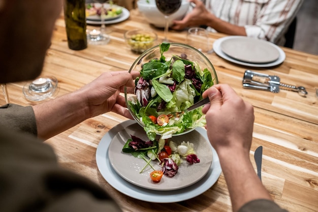 Mann isst Salat bei Dinnerparty