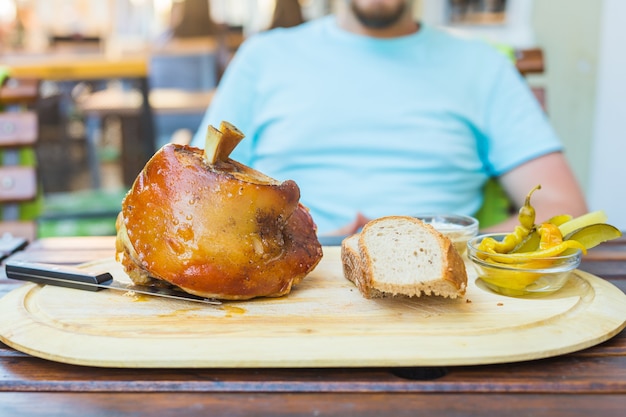 Mann isst Schweinshaxe und trinkt Bier