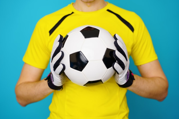 Mann ist Fußballfan im gelben T-Shirt mit Fußball auf Blau