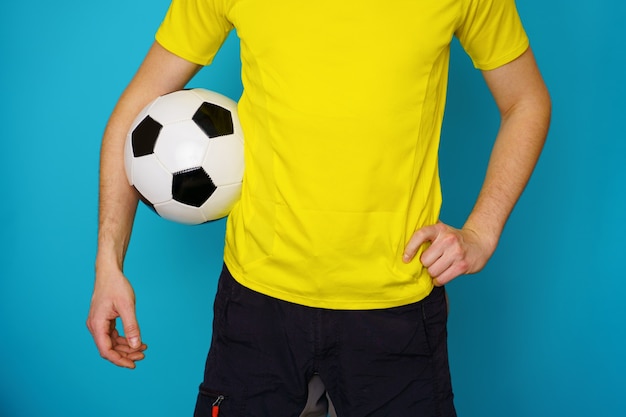 Mann ist Fußballfan in gelbem T-Shirt mit Fußball auf blauem Hintergrund