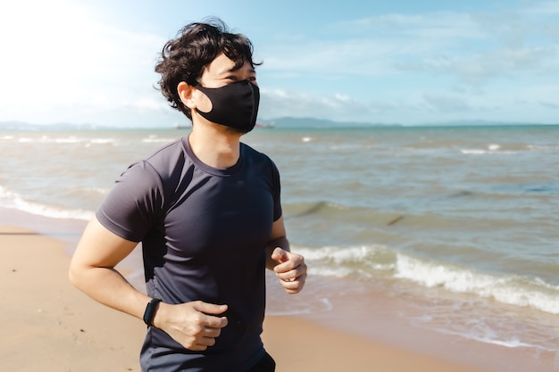 Mann joggt am Strand mit Maske im Sommermorgen