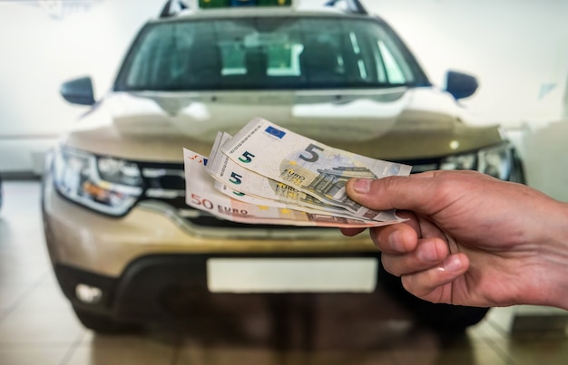 Mann kaufen neues Auto, das Euro-Banknoten gibt. Kaufkonzept finanzieren