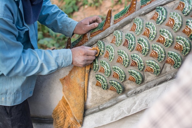 Mann klebt Keramikfliesen auf Naga-Treppe im Tempelbau Naga-Treppe in Thailand