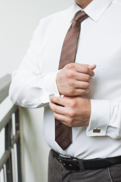 Mann knöpft Hemd ein Mann in einem weißen Hemd Morgenbräutigam Hände eines Mannes Nahaufnahme ein weißes Hemd