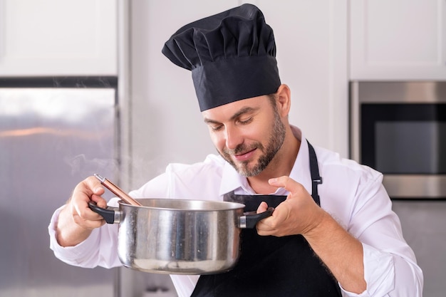 Mann kocht in der Küche. Schöner Mann bereitet köstliche Mahlzeiten in moderner Küche zu. Männlicher Koch kocht in