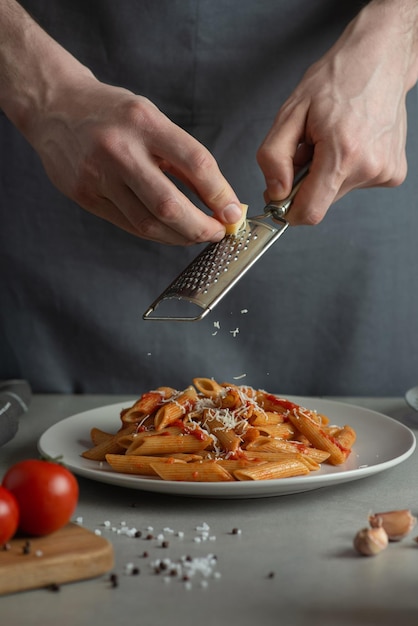 Mann kocht Nudeln und reibt Käse