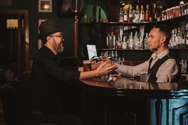 Mann kommuniziert mit einem Barkeeper an der Bar mit Bier