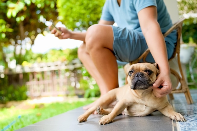 Mann kratzt den Hund im Garten