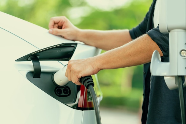 Foto mann laden batterie für elektroauto während straßenfahrt exalt