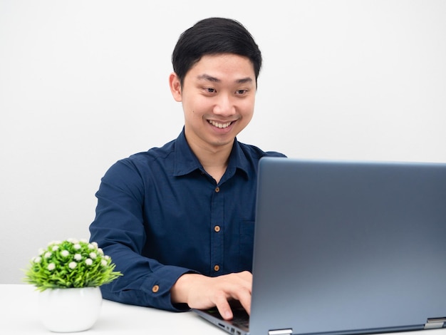 Mann lächelt mit Laptop in der Tischarbeit von zu Hause aus