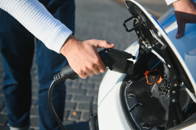 Mann lädt ein Elektroauto an der Ladestation