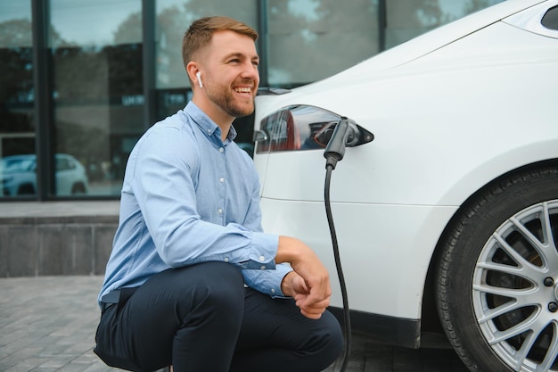 Mann lädt ein Elektroauto an der Ladestation