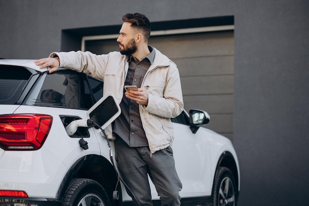 Mann lädt Elektroauto am Haus auf