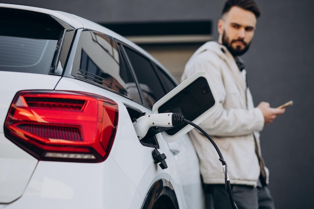 Mann lädt Elektroauto am Haus auf