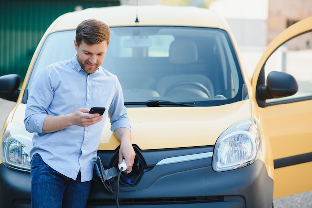 Mann lädt Elektroauto am Haus auf