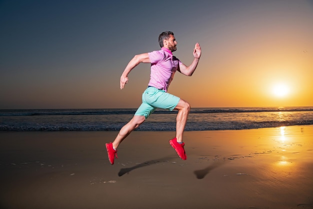 Mann läuft am Strand bei Sonnenuntergang Kerl Läufer Jogger läuft dynamische Sprungbewegung Sportsprung