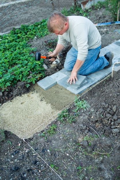 Mann legt Pflaster im Garten